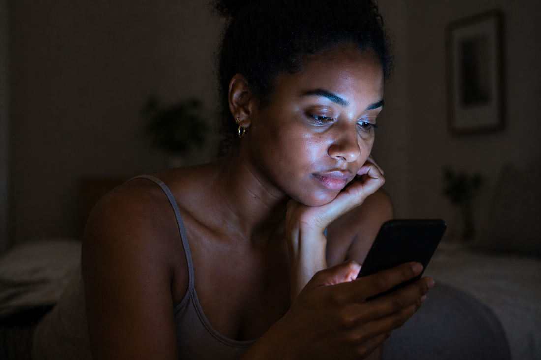 Young woman illuminated by phone screen at night, showing effects of blue light exposure on skin and digital aging