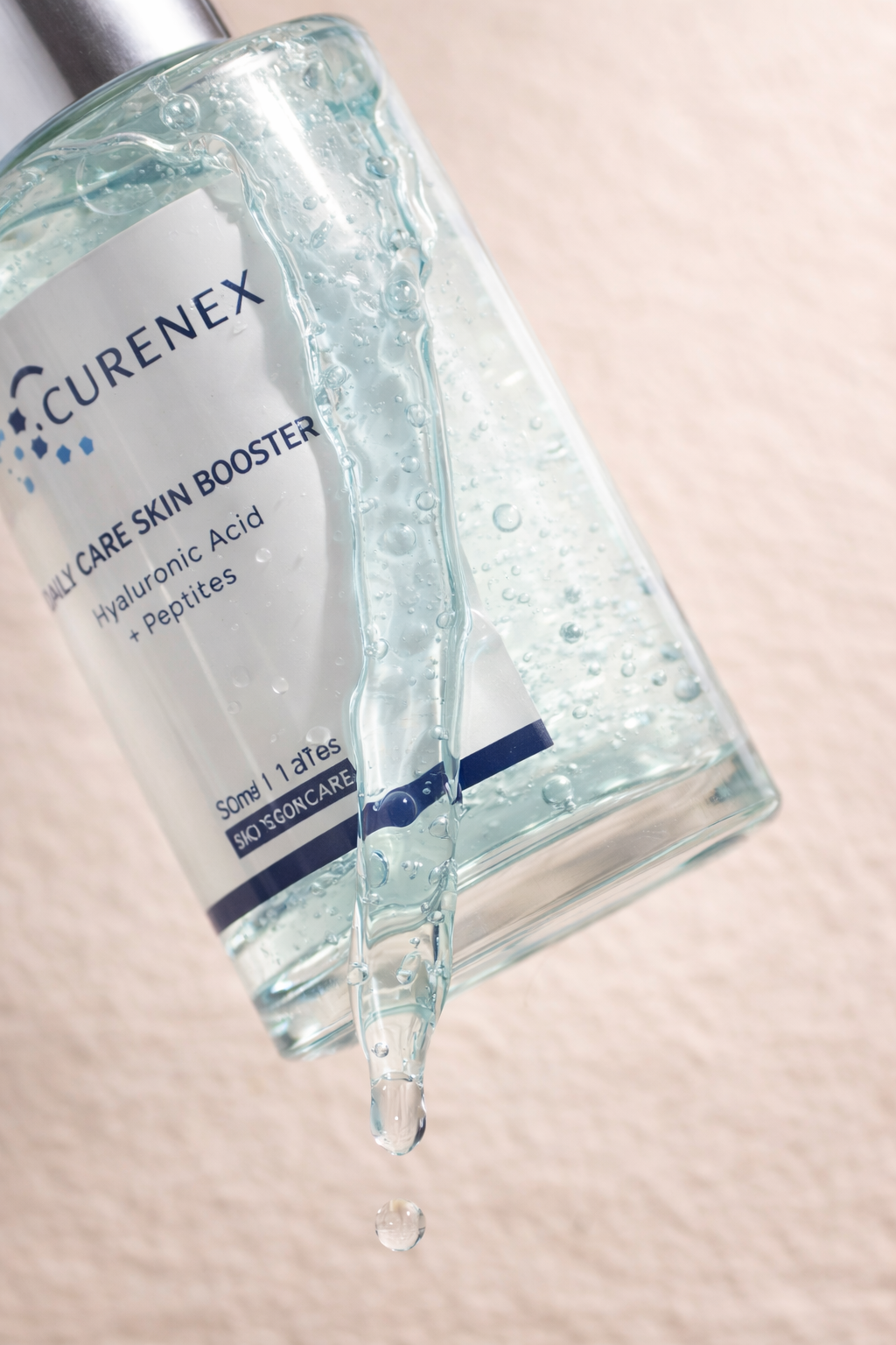 Curenex Daily Care Skin Booster bottle with droplet on a light pink background.