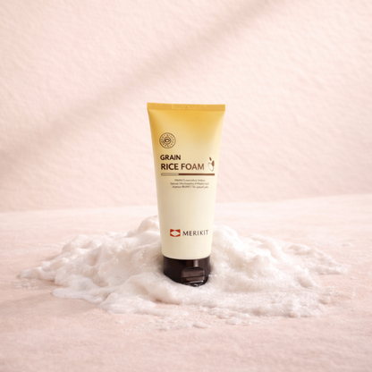 Tube of Merikit Grain Rice Foam on a pink background with foam around it.